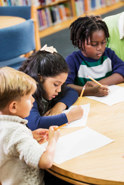 istock Hispanic girl, classmates in elementary school, writing 1172284614