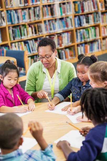 istock Teacher with children sitting at table, writing 1172284616