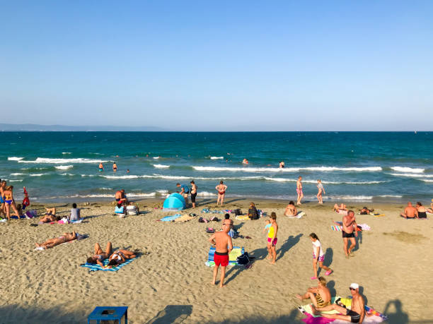 Calella de Palafrugell, Spain - July 10, 2022: Aerial view of beach with many people sunbathing on sand and swimming in turqoise colored waters of Costa Brava, Catalonia. Spain
