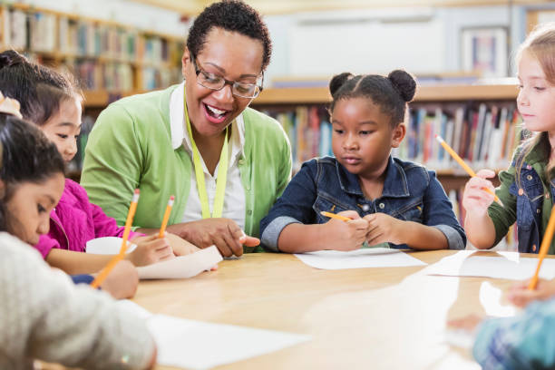 istock Teacher with children sitting at table, writing 1172285200