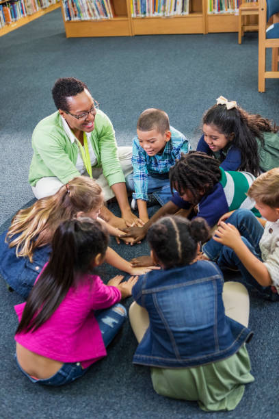 учитель, ученики нача�льной школы, сидящие в кругу - circle group of people human hand student стоковые фото и изображения