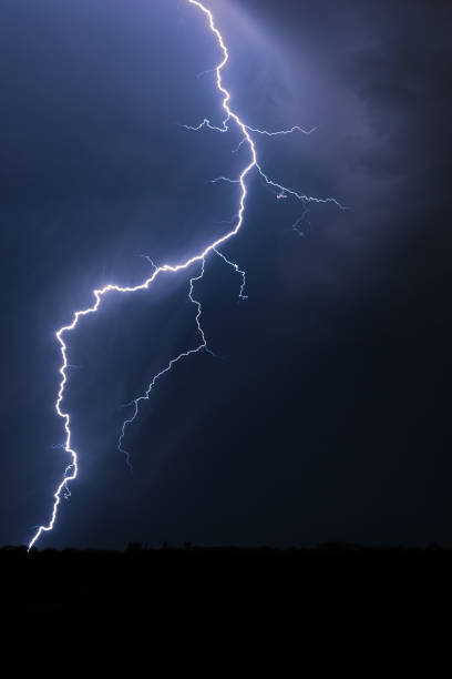 istock Vertical view of forked lightning bolt striking down to earth 1172289675