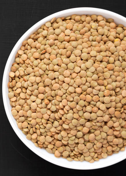 istock Organic green lentils in a white bowl on a black surface, top view. Flat lay, overhead, from above. Close-up. 1172291377