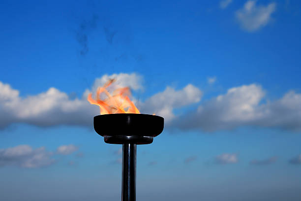 glory burning torch burning flaming torch over cloudy sky. the olympic games stock pictures, royalty-free photos & images