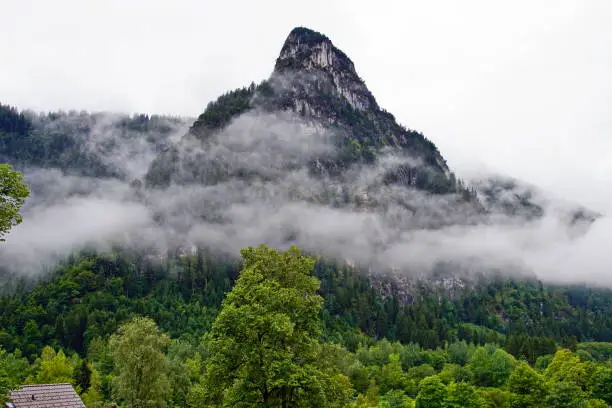 Oberammergau, Germany August 2019:  In the early morning, the Kofel is shrouded in thick fog, particularly after a rainy night.