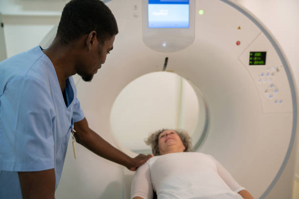 czarny przyjazny radiolog pocieszający starszą kobietę przed skanowaniem mózgu już leżącego gotowy do egzaminu - mri scanner healthcare and medicine medical exam brain zdjęcia i obrazy z banku zdjęć