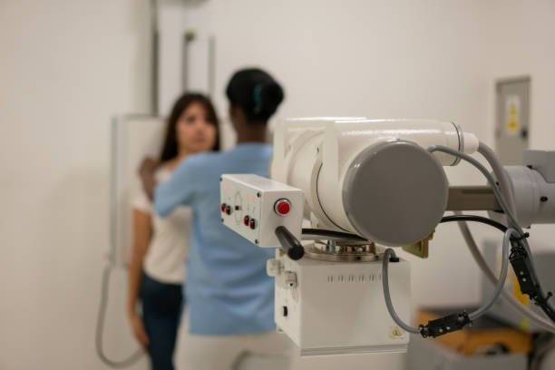 Unrecognizable technician getting ready female patient for a chest x ray - Focus on foreground