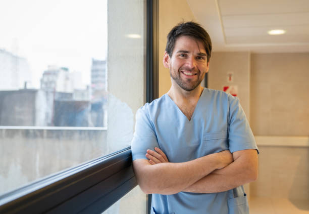 retrato de cirujano masculino latinoamericano frente a la cámara sonriendo con los brazos cruzados en el hospital - nurse doctor healthcare and medicine latin american and hispanic ethnicity fotografías e imágenes de stock