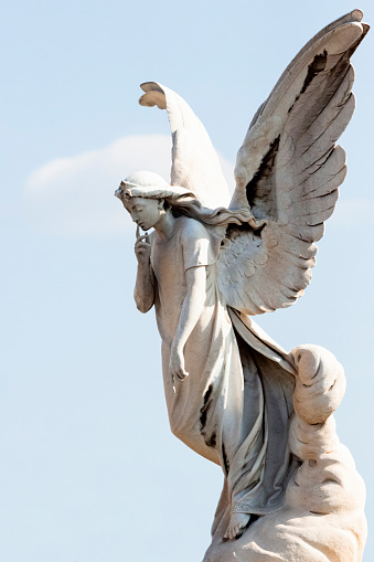Old statue of angle in cemetery build in 1850 France, sky background with copy space, vertical composition