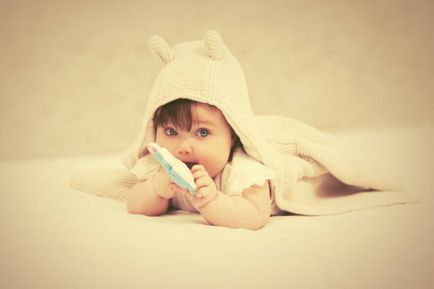 kuvapankkikuvat ja rojaltivapaat kuvat aiheesta tyttövauva leikkii lelulla peitossa kotona - one baby girl only