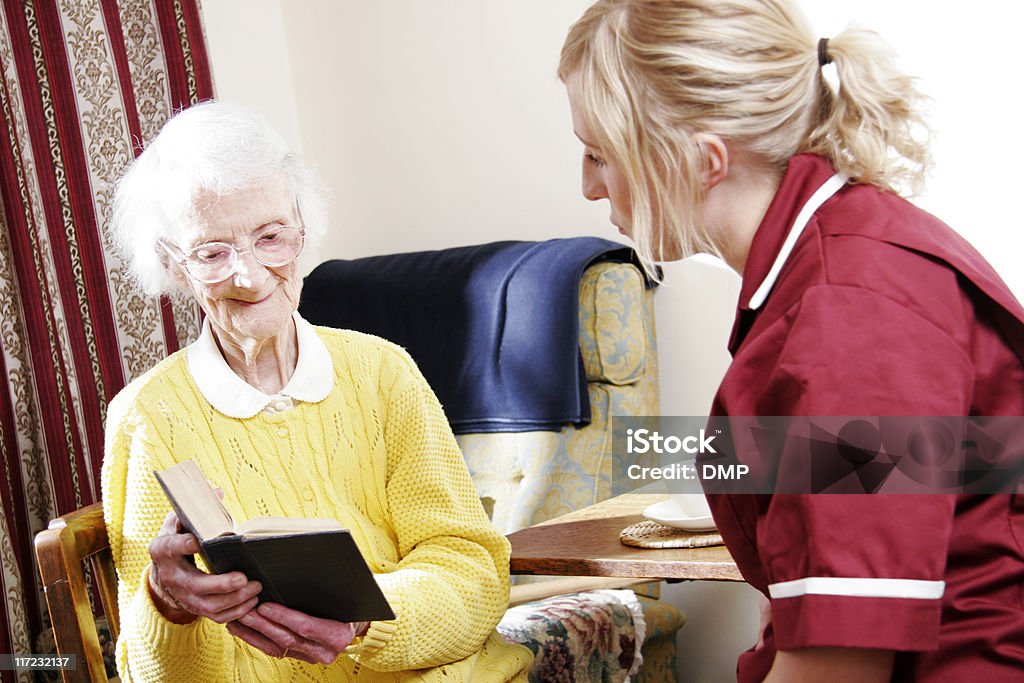 Junge Krankenschwester und senior Frau lesen Bibel in sich wie zu Hause - Lizenzfrei Aktiver Senior Stock-Foto