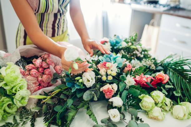 istock Florist woman creating flower composition at home. Worker composing wedding bouquet. Small business 1172324389