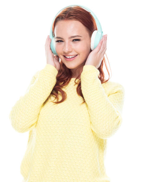 cintura acima de 18-19 anos de meninas adolescentes caucasianos das mulheres novas do redhead bonito velho na frente do fundo branco que desgasta calças de brim/camisola do cardigan que está sorrindo/feliz/alegre/que escuta que está suando e usando ausc - 18 19 years audio - fotografias e filmes do acervo