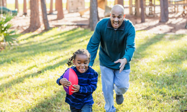 istock Hispanic father chasing son on playground, football 1172332072