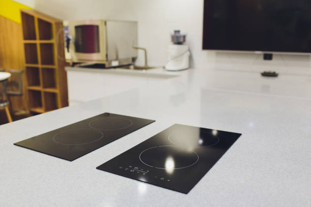 istock Modern black induction cooker on white countertop. kitchen with island. 1172334768