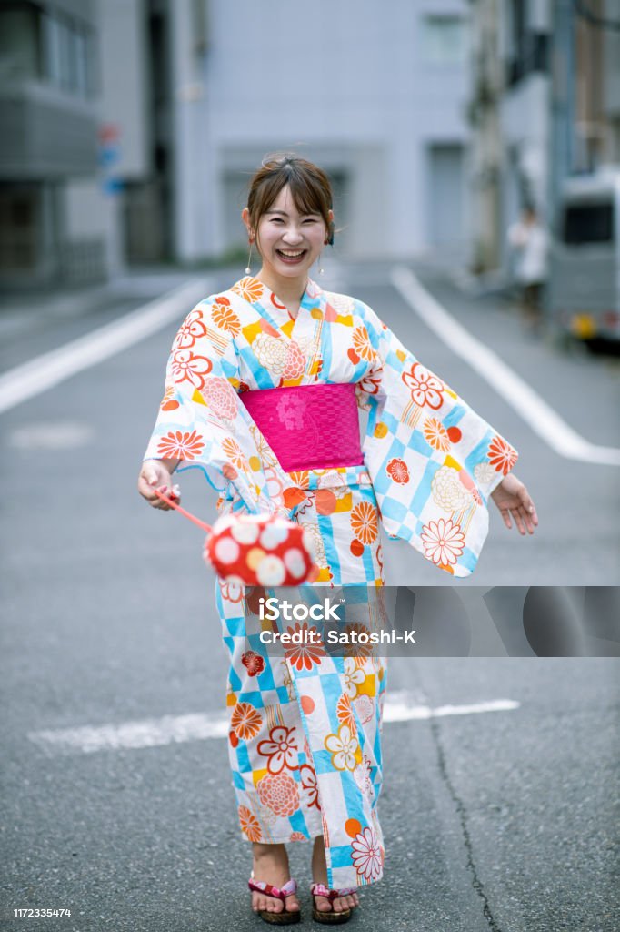 Happy young woman in yukata standing on street Japan Stock Photo