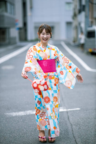 Happy young woman in yukata standing on street Happy young woman in yukata standing on street geta sandal stock pictures, royalty-free photos & images