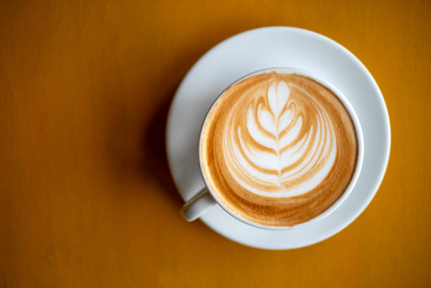 istock A white cup of cappuccino with latte art on brown wood table with low light 1172344302