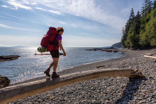 Adventurous girl hiking Juan de Fuca Trail to Chin Beach on the Pacific Ocean Coast during a sunny summer day. Taken near Port Renfrew, Vancouver Island, BC, Canada.