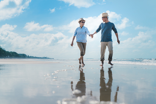 Asian couple senior elder retire resting relax walking running at sunset beach honeymoon family together happiness people lifestyle