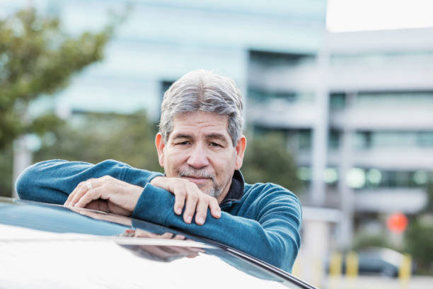 istock Senior Hispanic man leaning on car, in city 1172351095