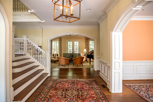 Grand and elegant yellow entrance to a home with stairs. Oriental rug and wood and glass door