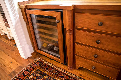 Stained wood Butler's pantry wine bottle refrigerator and glasses storage. Includes wine glasses and storage for decorative dishes.
