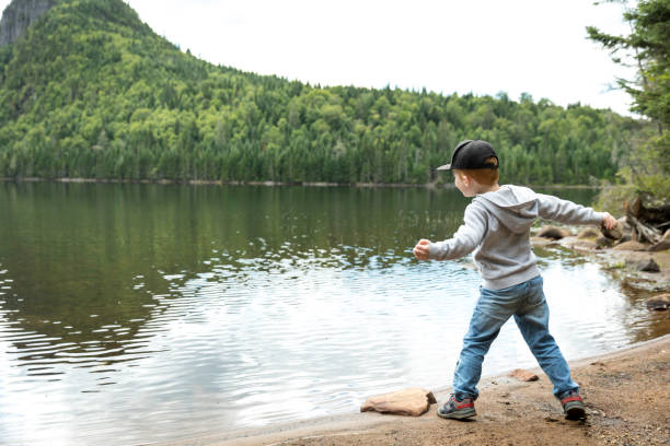 istock Little Redhead Boy Throwing Rocks In Lake in Summer 1172362484