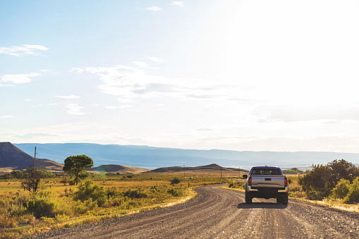 Near Grand Junction Colorado Pickup Truck on gravel road in desert plain area long Western USA Roads Highways Desert and Mountains (Shot with Canon 5DS 50.6mp photos professionally retouched - Lightroom / Photoshop - original size 5792 x 8688 downsampled as needed for clarity and select focus used for dramatic effect)