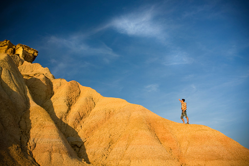 Man with arms wide open and the sky as background, in bardenas reales desert ( navarre, Spain )