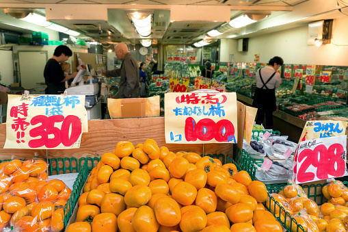 Tokyo, Japan - October 4, 2019 :  fresh japanese fuyu persimmon selling in fruit and vegetable local greengrocer shop at the market in Tokyo, Japan.