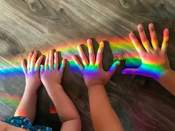 Small children’s hands playing with a rainbow on the floor
