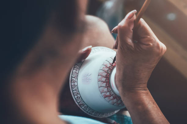 A worker is decorating a porcelain cup in a ceramic factory in China.