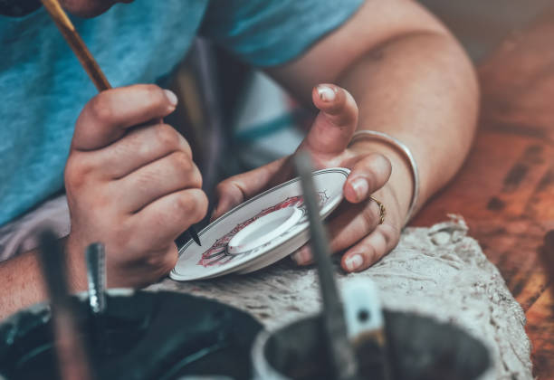 A worker is decorating a porcelain cup in a ceramic factory in China.