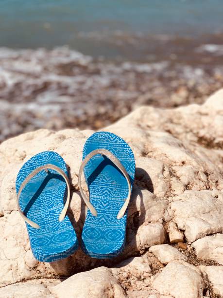 Sandals or flip flops on the stone beach on sea background