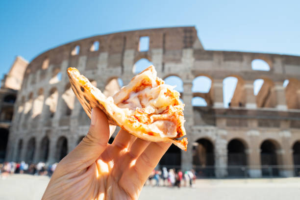 hand holding italian pizza near colosseum - flavian amphitheater fotos imagens e fotografias de stock