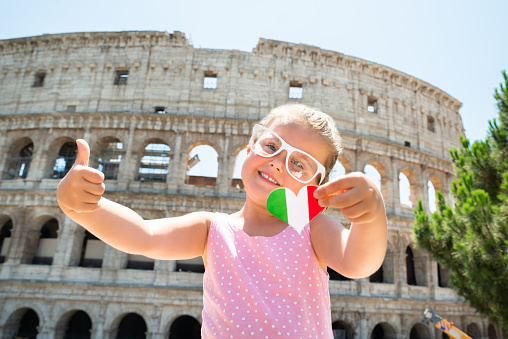 Girl Wearing Italian Flag Sunglasses, Holding Heart And Showing Thumb Up Near Colosseum, Rome, Italy