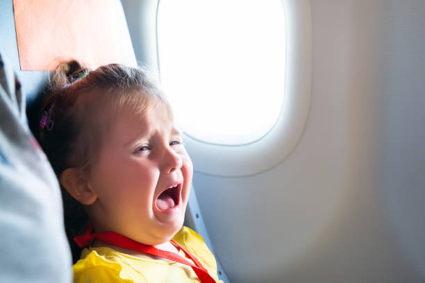 Girl Screaming On Airplane Little Girl Sitting Next To Mother Screaming On Airplane baby crying on plane stock pictures, royalty-free photos & images