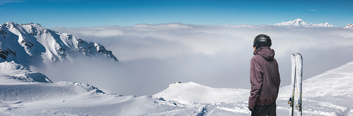 Skier enjoying the view on the top of the mountain. This image is a composite.