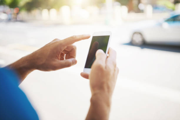 Cropped shot of an unrecognizable man using his cellphone while out in the city