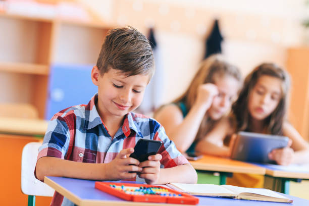 istock Schoolboy use a mobile phone in the classroom 1172398690