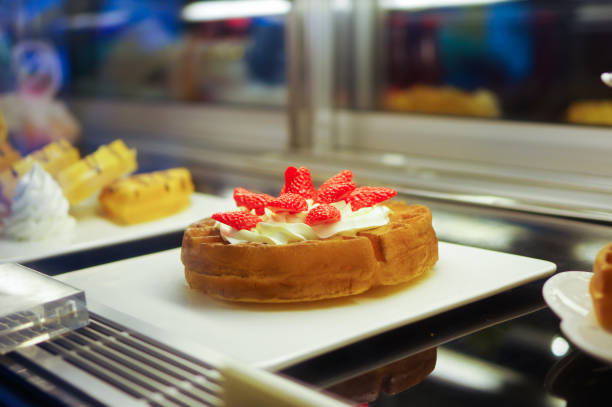 Fake strawberry cream waffle props model displayed on white plate in cafe refrigerator