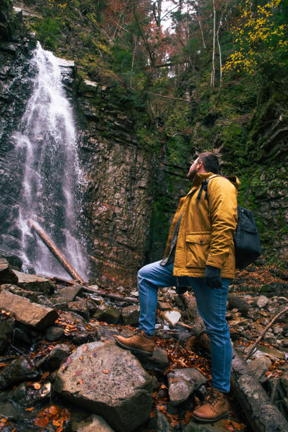istock man hiking concept looking at waterfall in dip forest 1172410595