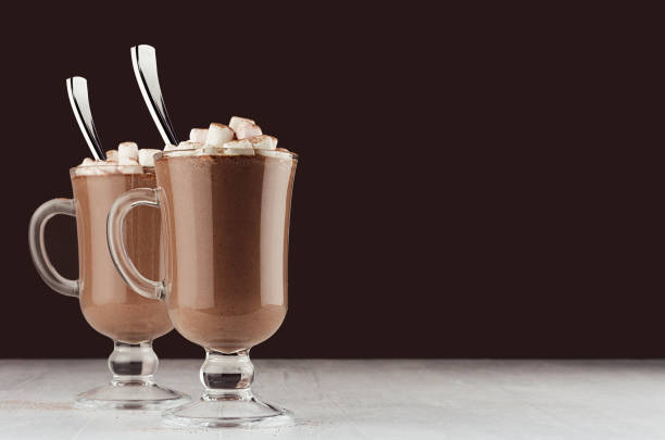 istock Elegant hot chocolate in two glass with marshmallows and silver spoon on dark brown background, copy space. 1172411509