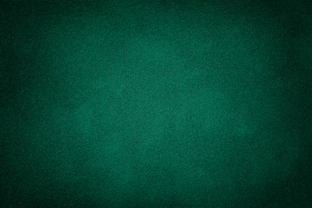 Dark green matt suede fabric closeup. Velvet texture. Dark green matte background of suede fabric, closeup. Velvet texture of seamless deep emerald leather. Felt material macro with vignette. emerald green photos stock pictures, royalty-free photos & images