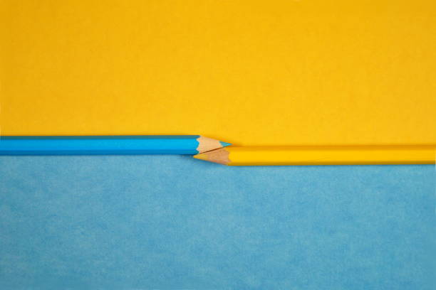 istock multicolored pencils on a yellow and light blue universal two tones paper background. two multicolored pens, two tones of a two-color substrate. top view close up. Office Supplies, supplies for home. 1172418260