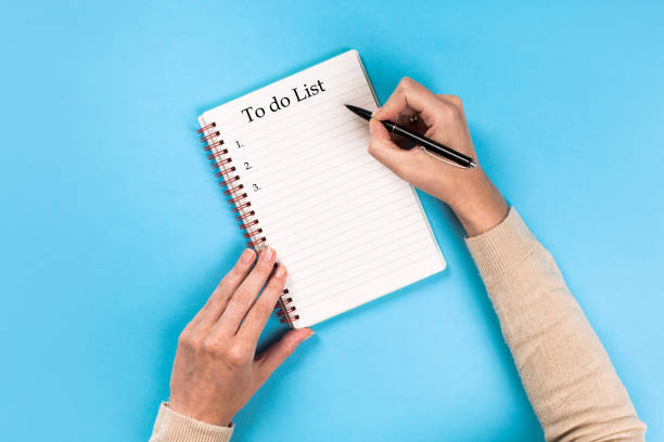 istock To do list Concept - 2020 number and text on notepad .Woman's hands with perfect manicure holding pencil and  notepad as mockup for your design. blue background, flat lay 1172418665