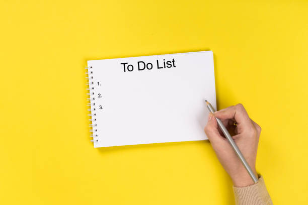 istock Woman's hands with perfect manicure holding pencil and  notepad as mockup for your design. Yellow background, flat lay 1172420366