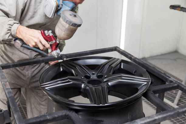 peinture du corps de l'élément de la voiture - la roue en alliage d'aluminium à l'aide de aerograf en couleur noire par la main du réparateur peintre dans le garage professionnel industriel. industrie des services automobiles. - airbrush machine airbrushing paint photos et images de collection