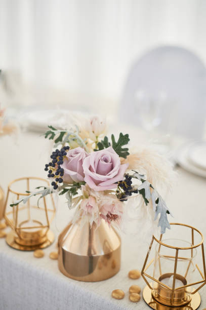 istock Wedding decoration in boho style.Light colors, in the tent. Wedding table decorated with gold vases with roses and cereals. And geometric candles in gold candlesticks 1172421165